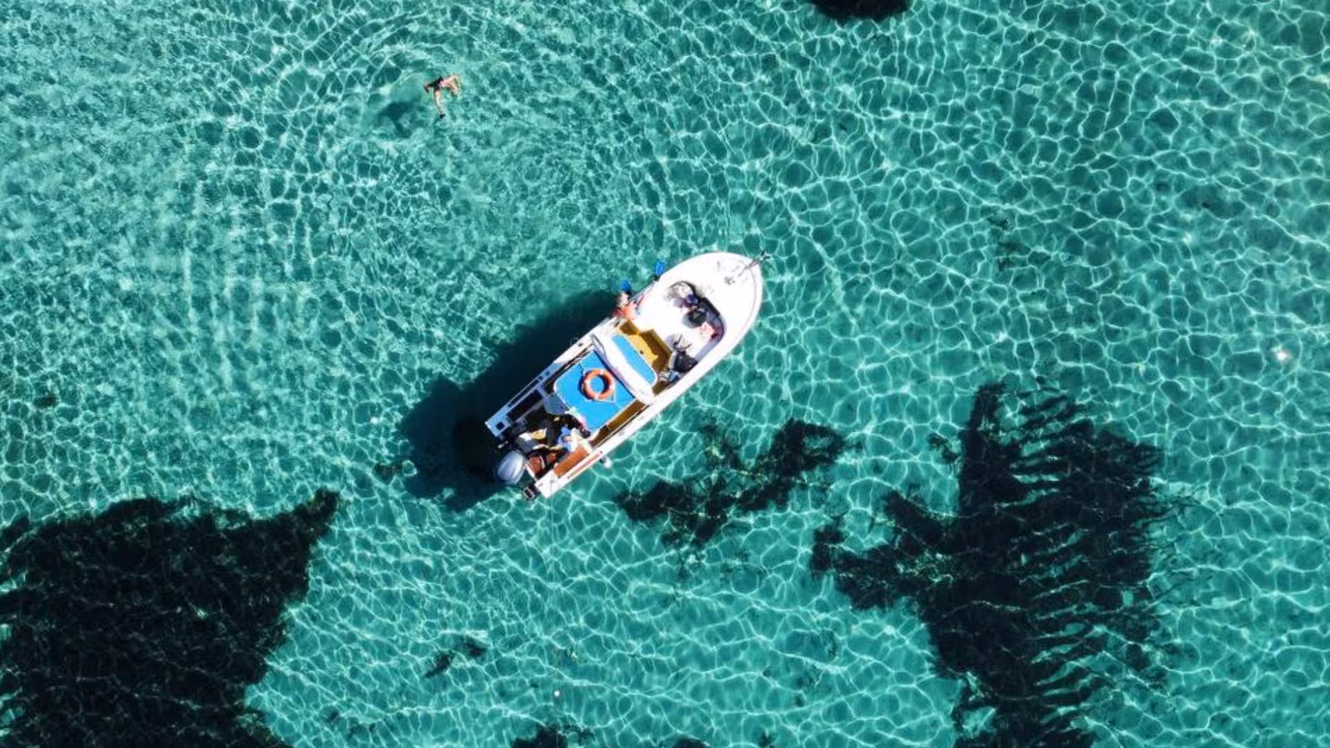 Aerial view of a boat in crystal-clear waters near Asinara during a Stintino boat trip with aperitif.