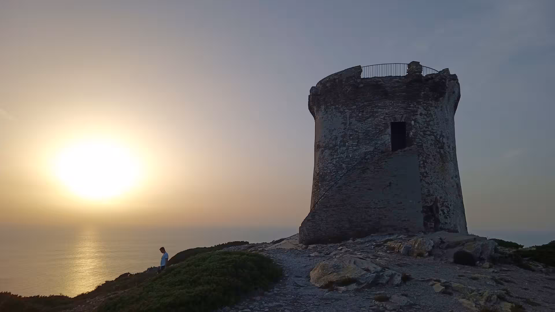 Silhouette of a historic tower at Capo Falcone during sunset, highlighting the scenic beauty of Stintino's coastal hike.