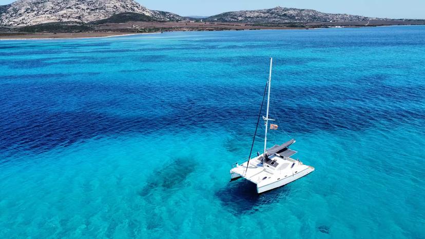 Catamaran anchored in vibrant turquoise waters near Asinara Island, showcasing the stunning coastal scenery of Stintino.