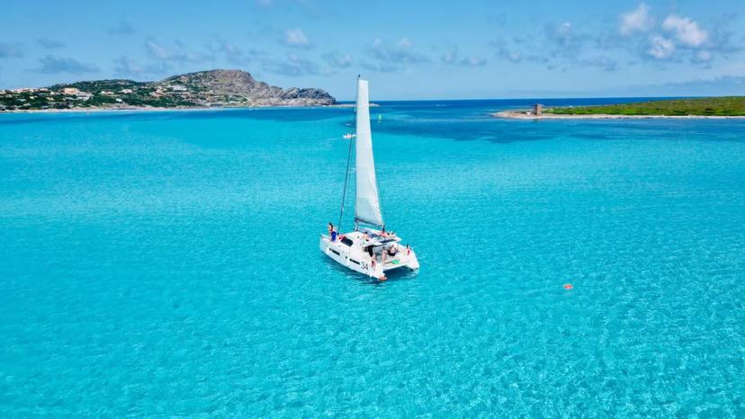 Catamaran sailing in La Pelosa's crystal-clear waters near Stintino, offering a perfect day for relaxation and exploration.