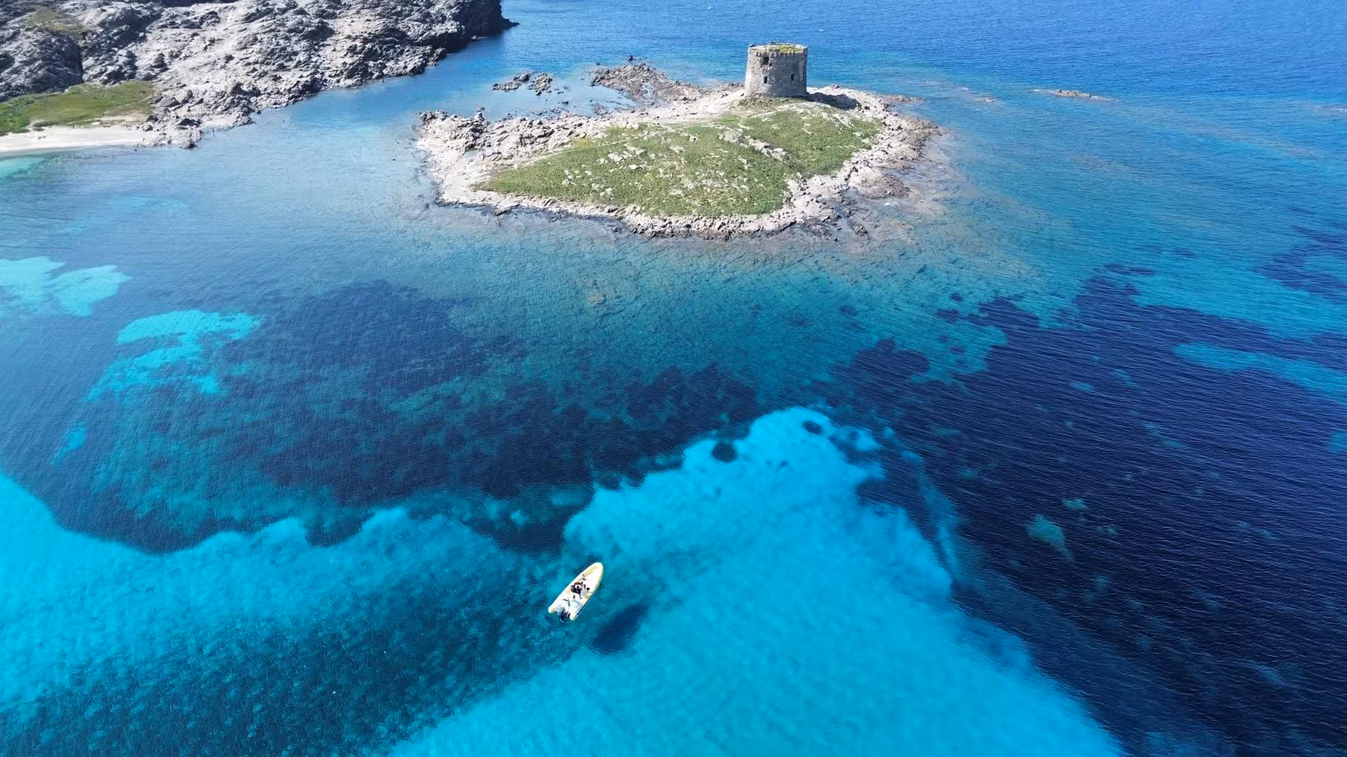 Aerial view of a dinghy near Asinara Island's turquoise waters and rocky coastline, perfect for Stintino boat tours.