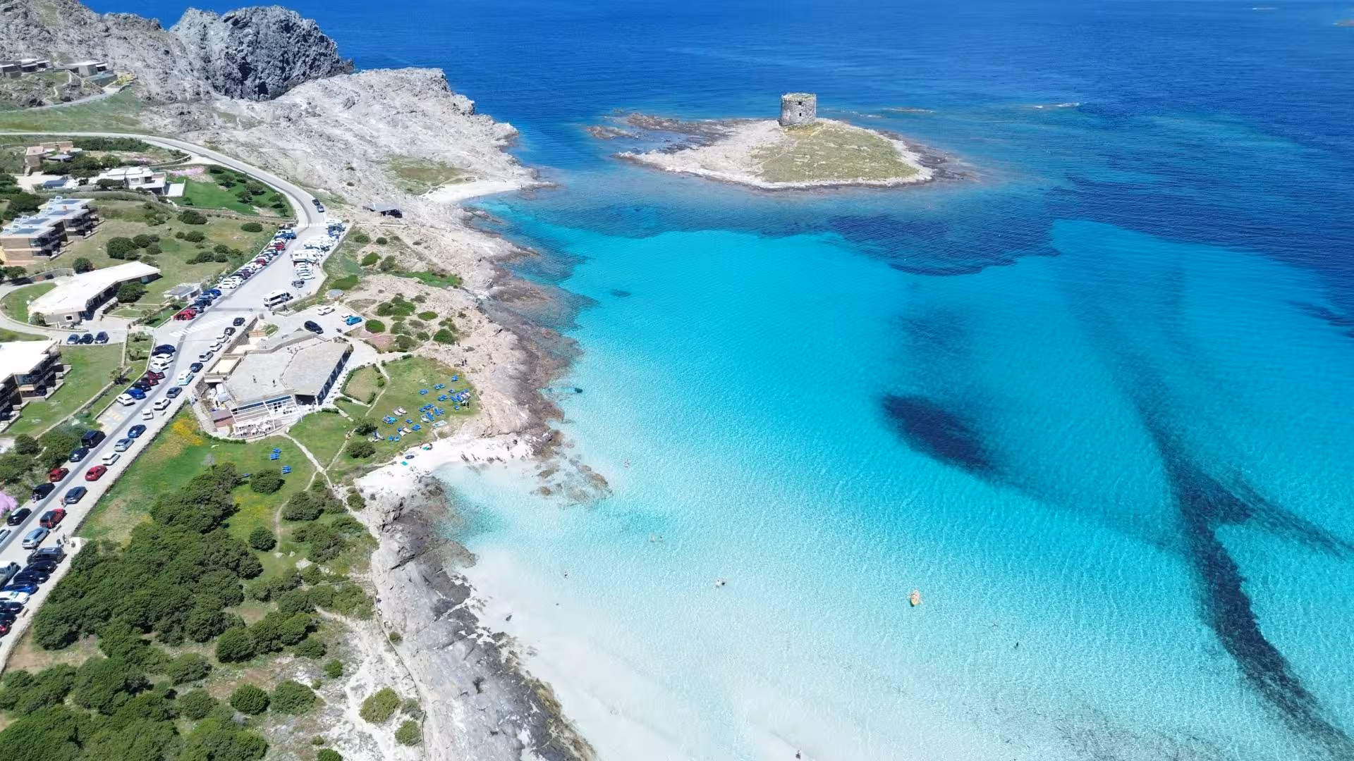 Aerial view of Stintino's La Pelosa Beach with turquoise waters and ancient watchtower, ideal for Asinara dinghy tours.