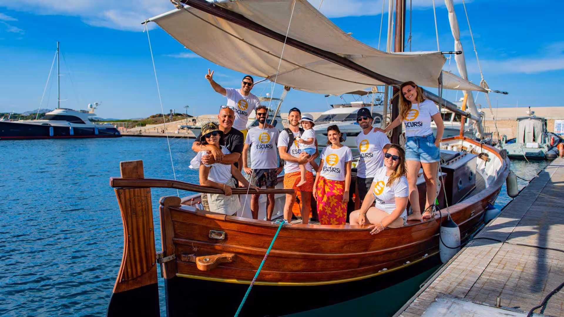 Group of happy tourists on a wooden sailboat docked in Stintino, ready for an adventure to Asinara Island.