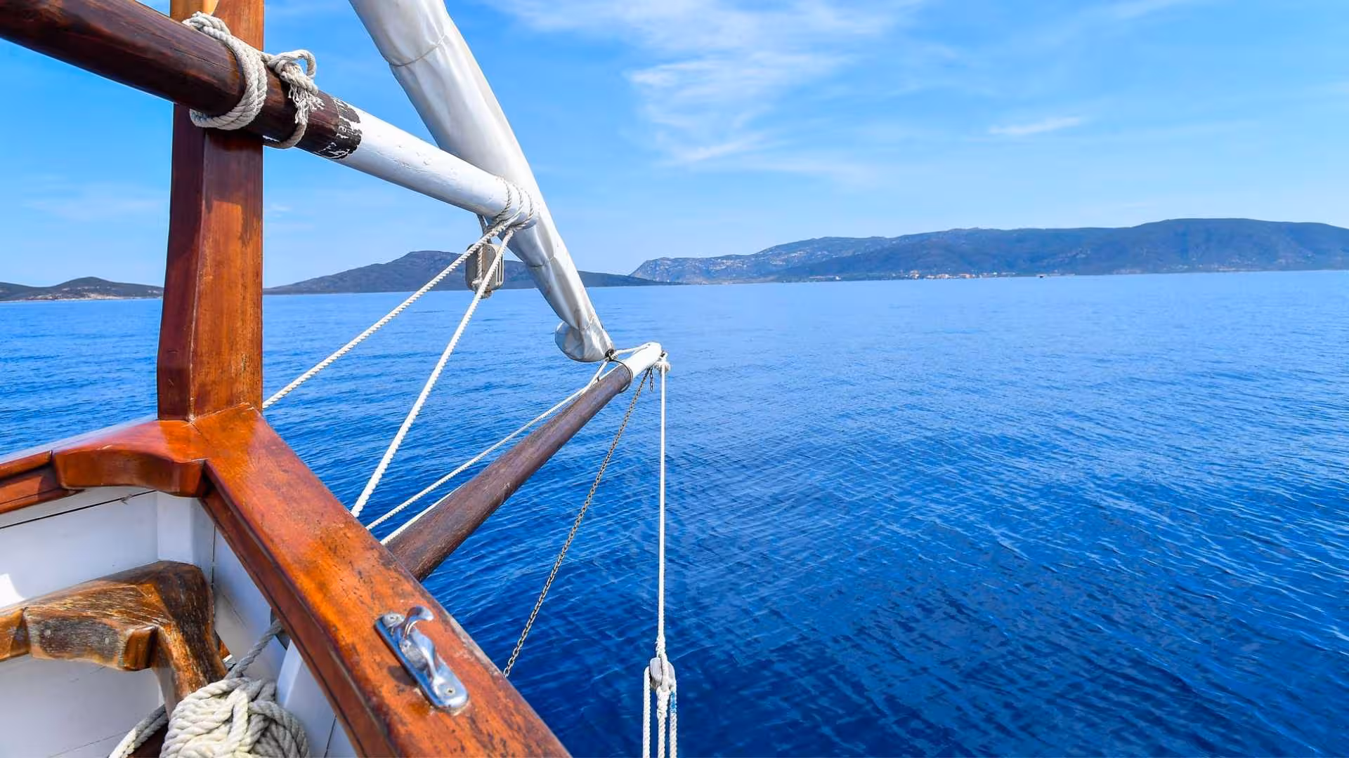 View from a sailboat cruising towards Asinara Island under a clear blue sky on a sailing trip from Stintino.