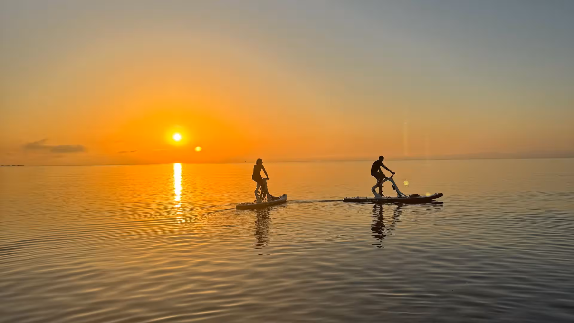 Two people enjoy a sunset water bike excursion across the calm waters of La Pelosa in Stintino.