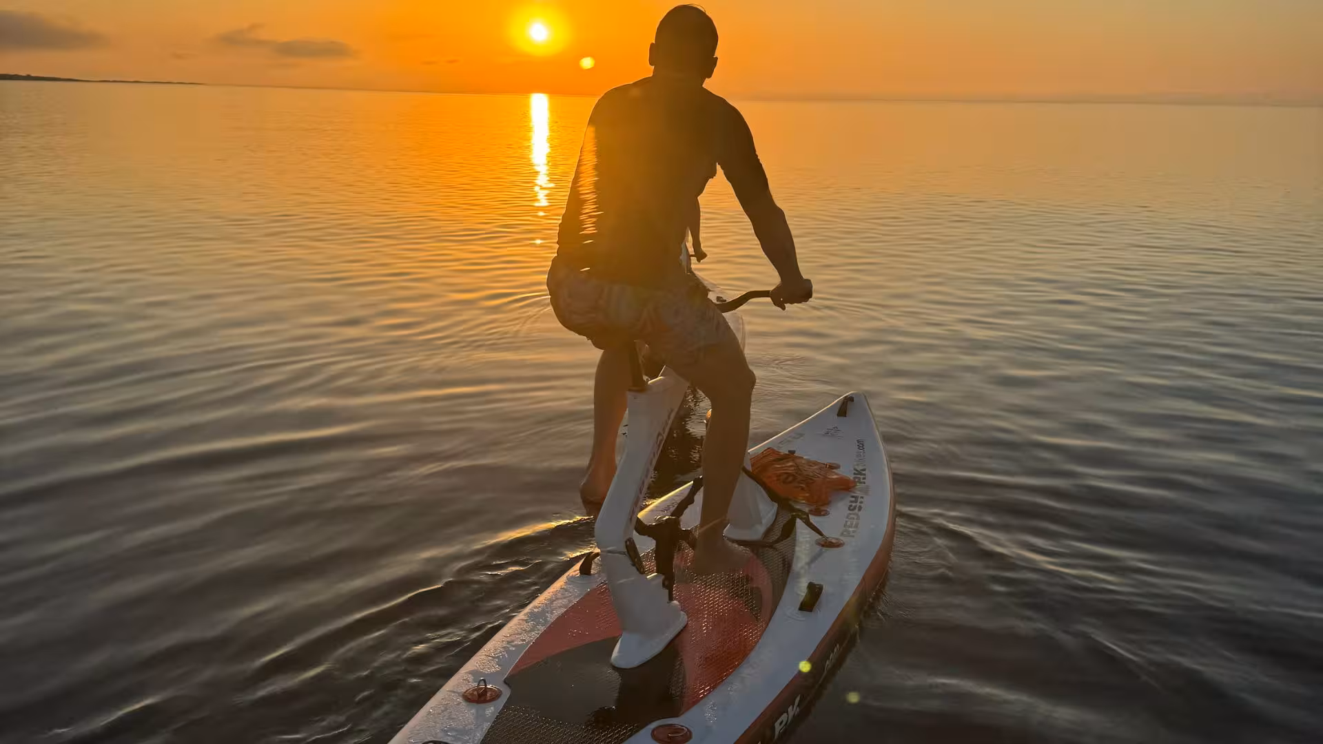 A person pedals a water bike towards the sunset on a serene La Pelosa excursion in Stintino.