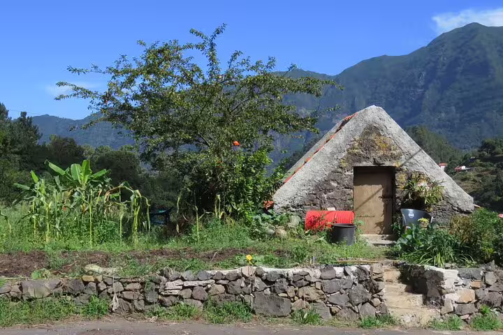 Rustic stone cottage surrounded by lush greenery and mountains, perfect for a scenic half-day jeep wine tour and tasting.