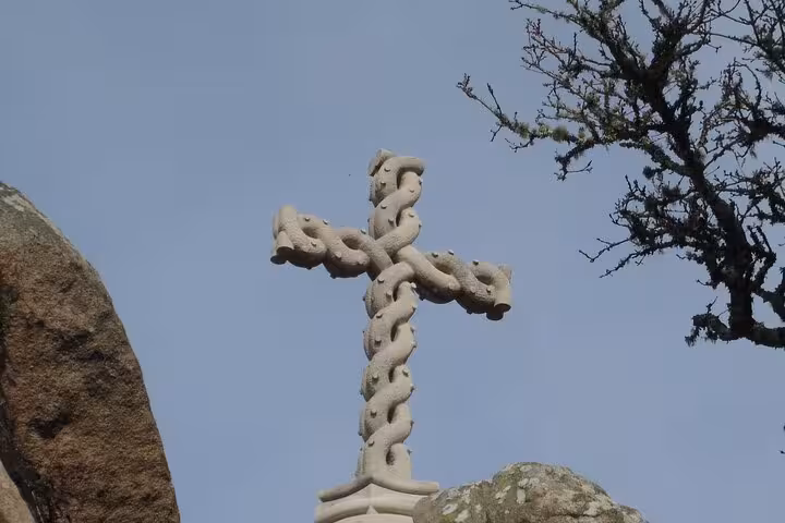 Intricate stone cross entwined with carvings at the highest point in Sintra, surrounded by natural scenery.