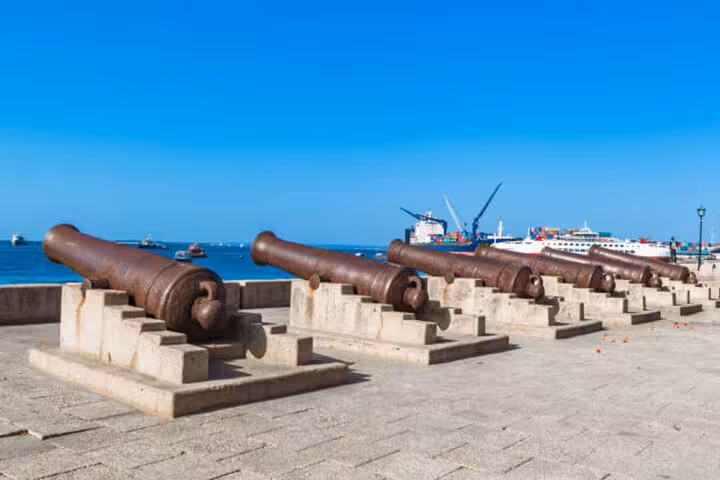 Historic cannons facing the Indian Ocean in Stone Town, Zanzibar, on a sunny day, highlighting maritime heritage.