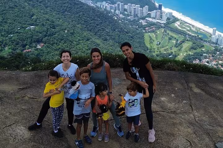 Group of tourists enjoying panoramic city and ocean views on a stone trail in DA Tijuca Forest.