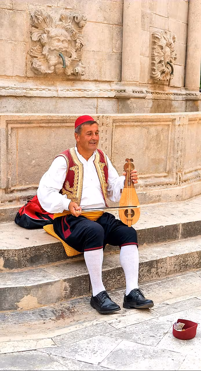 Street musician in traditional costume in Dubrovnik Old Town, cultural stop on a one day trip from Split