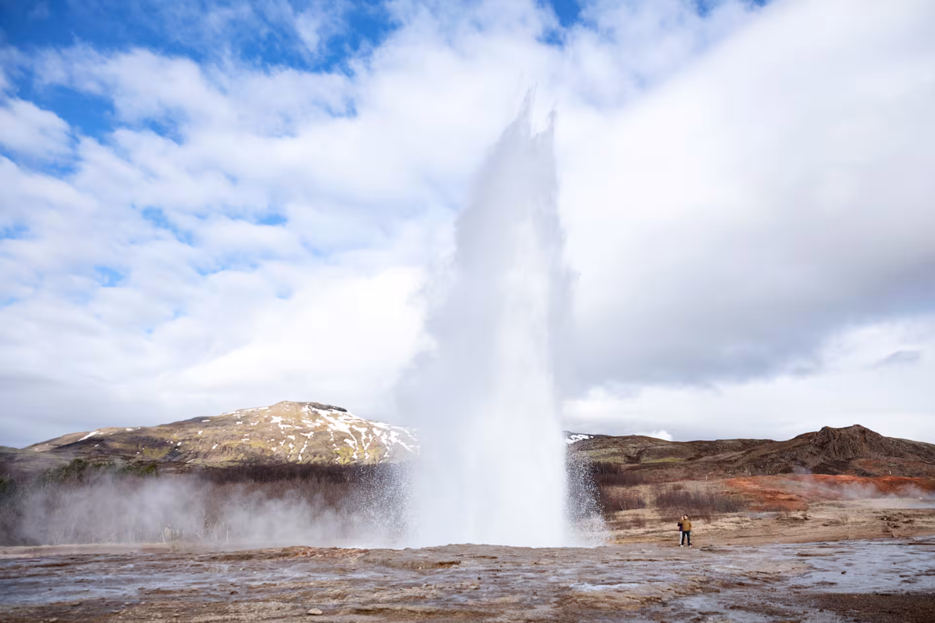 Strokkur geyser erupting in the Geysir area on Iceland Golden Circle tour, with steam and mountains