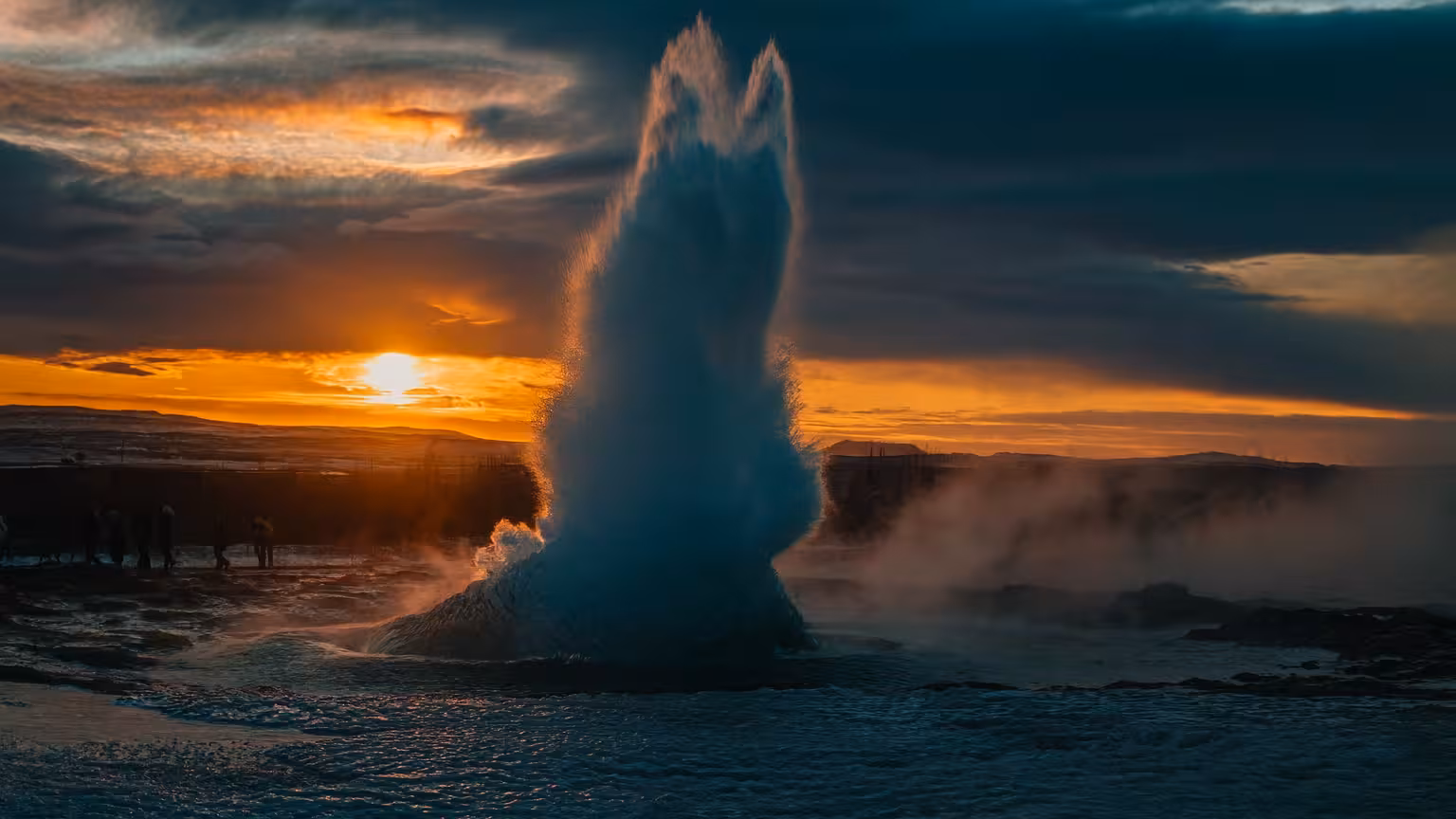 Strokkur geyser erupts dramatically against a vibrant Icelandic sunset on the Golden Circle Private Tour.