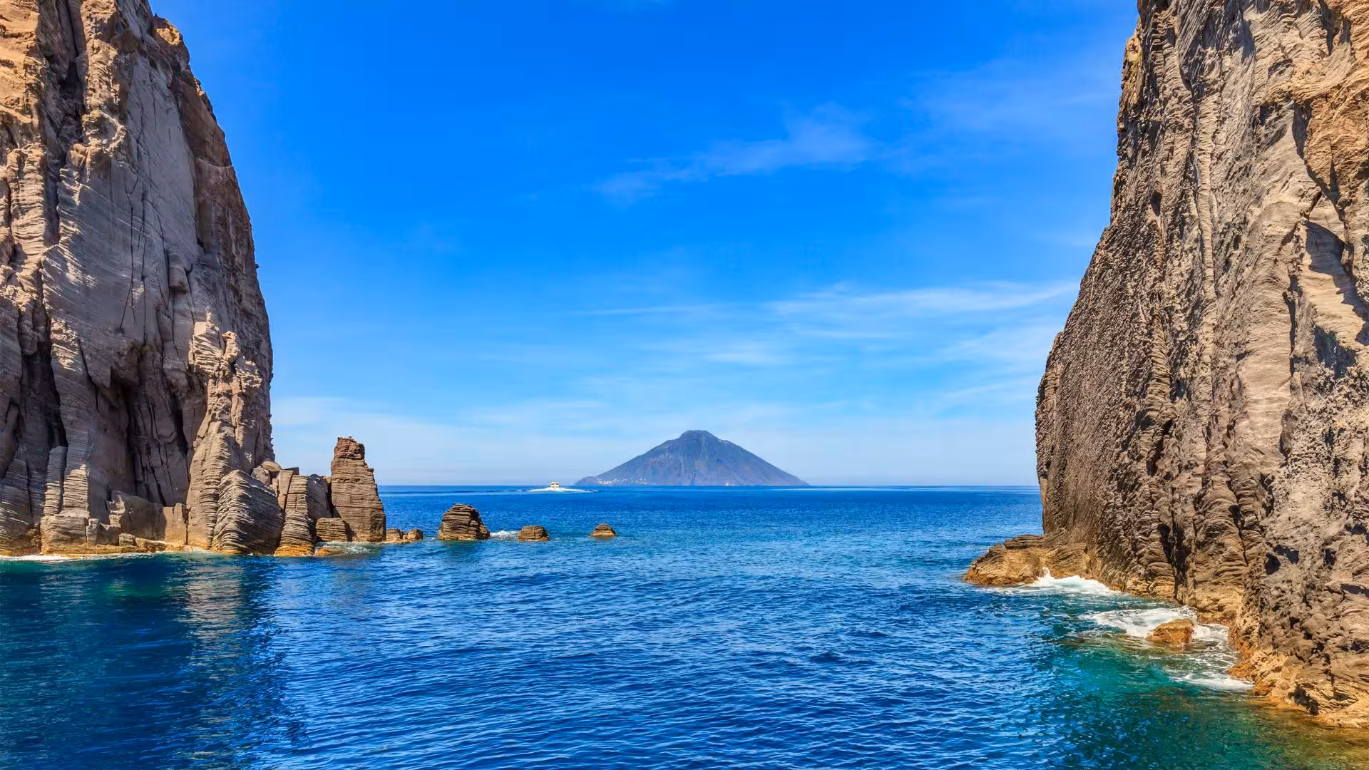 Stunning view of Stromboli volcano framed by rocky cliffs on an Aeolian Islands cruise.