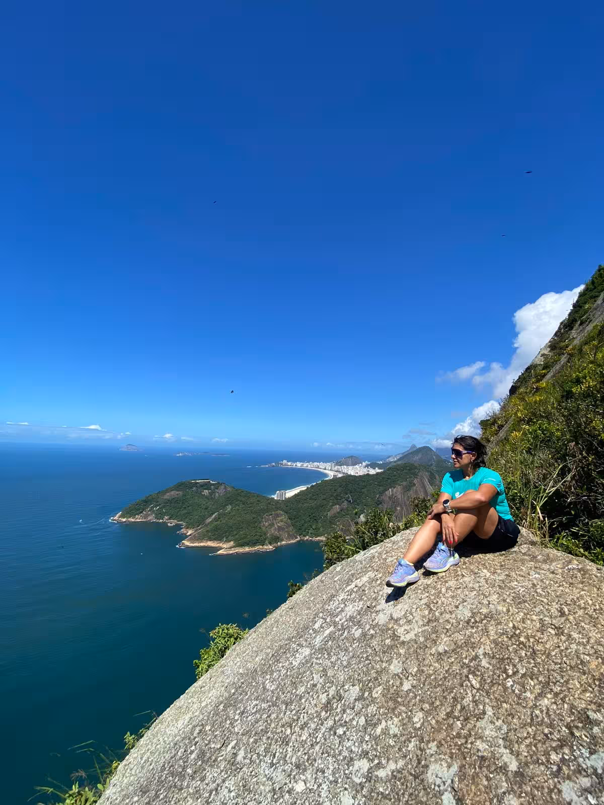Person enjoying a scenic rest atop Sugarloaf Rock overlooking the ocean, a must-visit for climbers of all levels.