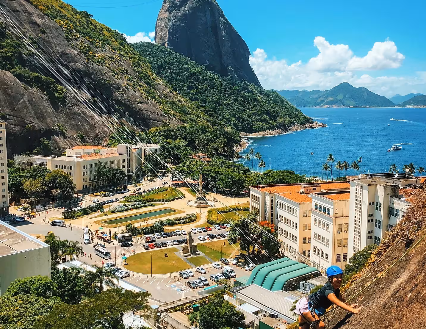 Climber ascends Sugarloaf Rock with panoramic views of cityscape and ocean, ideal for all-level rock climbing tours.