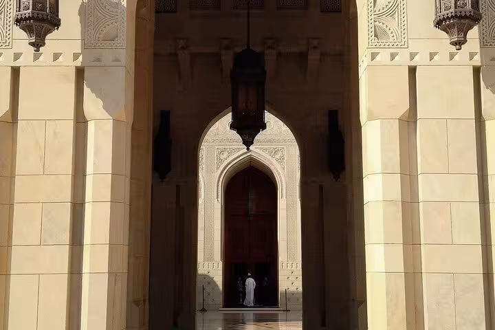 Intricate archway and hanging lanterns at the entrance of Sultan Qaboos Grand Mosque captured on a guided Muscat city tour