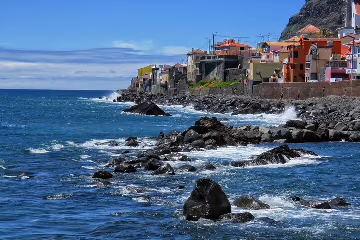 Colorful coastal village with rocky shoreline and vibrant sea, ideal for the "Sunny Southwest, Rum, Banana, Waterfall and Lighthouse Discovery" tour.