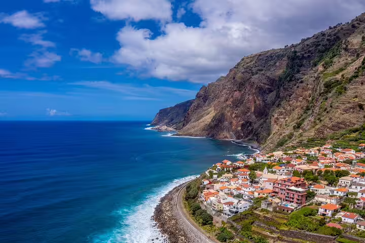 Scenic coastal view of the sunny southwest with rocky cliffs, vibrant village, and ocean waves, ideal for a rum and lighthouse tour.