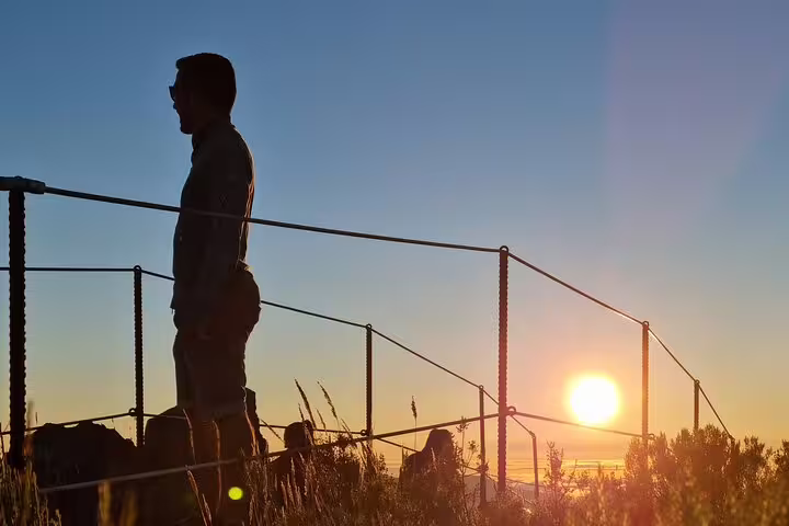Silhouette of a person enjoying a breathtaking sunrise at Areeiro Peak, Madeira, with vibrant skies and scenic views.