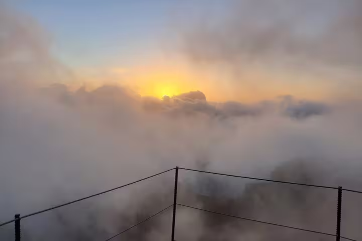 Breathtaking sunrise over Areeiro Peak with misty clouds and vibrant colors, perfect for a serene mountain viewing experience.