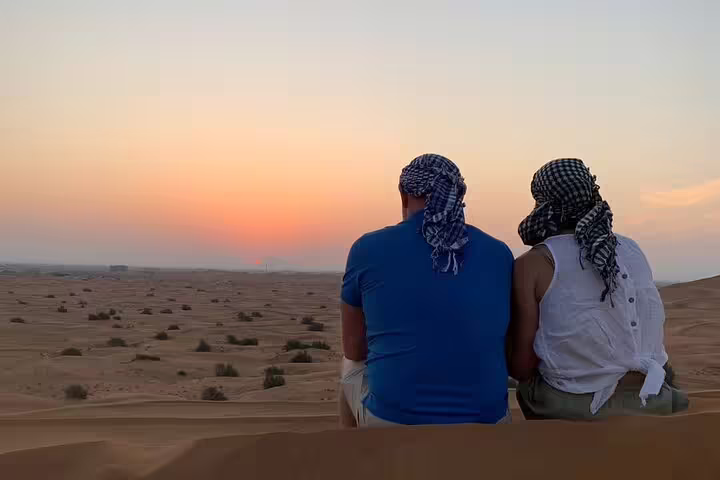 Couple watching a breathtaking sunrise over Dubai's desert landscape during a private safari.
