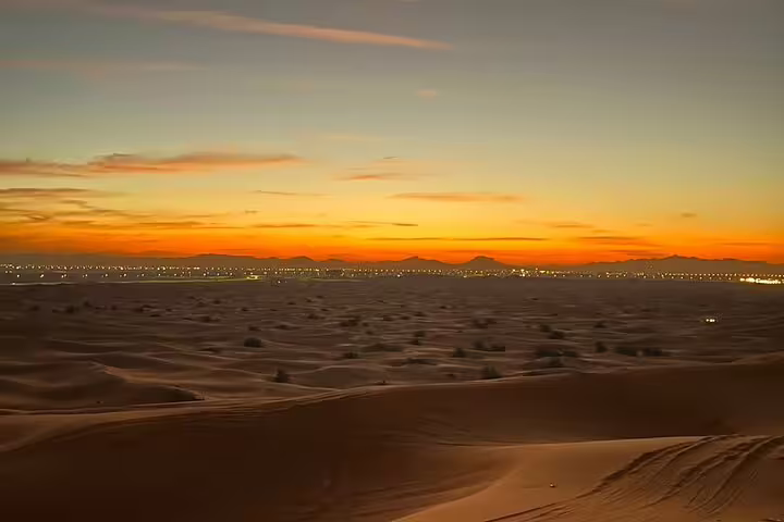Stunning sunrise over Dubai desert with sprawling sand dunes and distant city lights.