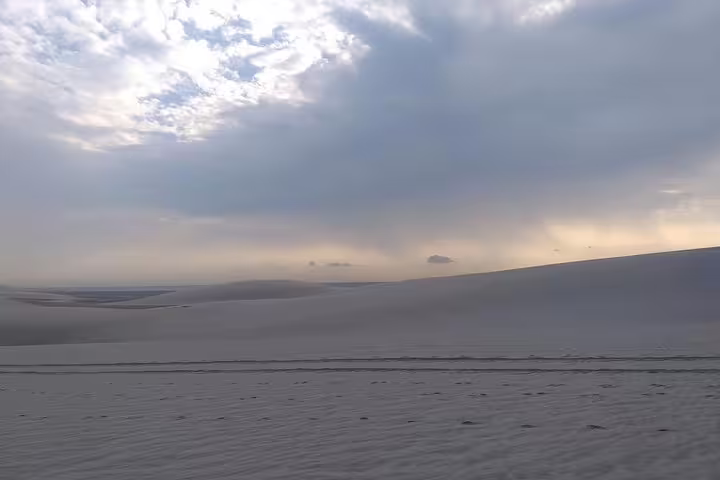 Tranquil desert landscape with soft sand dunes and a dramatic sunrise sky in Qatar's desert safari.