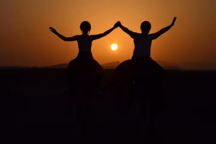Two riders celebrate at sunrise on horseback in Marsa Alam, scenic desert ride near the beach at dawn