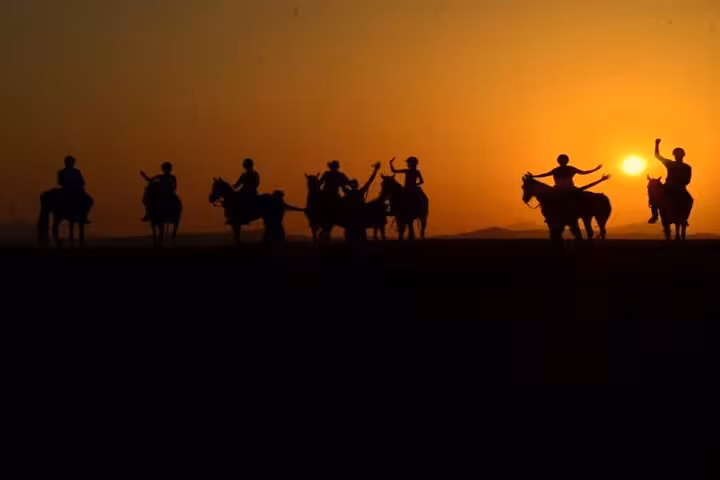 Group sunrise horse riding in Marsa Alam desert, silhouettes on ridge with golden dawn over Red Sea