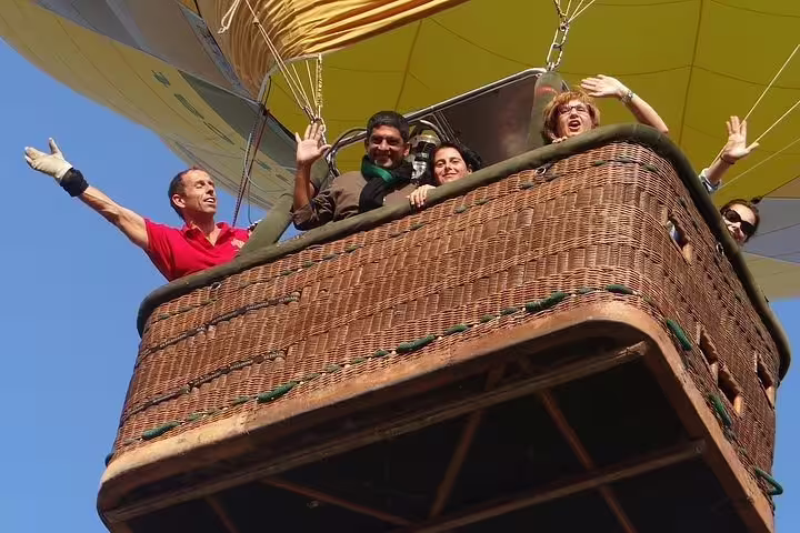 Group of happy tourists enjoying a hot air balloon ride over Igualada, capturing excitement and adventure in the sky.