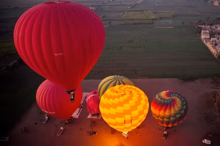 Colorful hot air balloon floating at sunrise in Luxor, Egypt, with hotel pickup and drop-off included