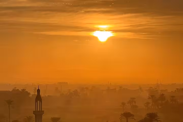 Golden sunrise over Luxor skyline and palm trees, scenic view on hot air balloon ride with transfers
