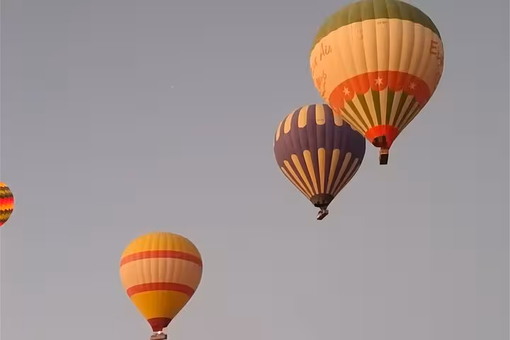 Colorful hot air balloons drift gracefully in the early morning sky over Luxor West Bank, perfect for an unforgettable sunrise tour.
