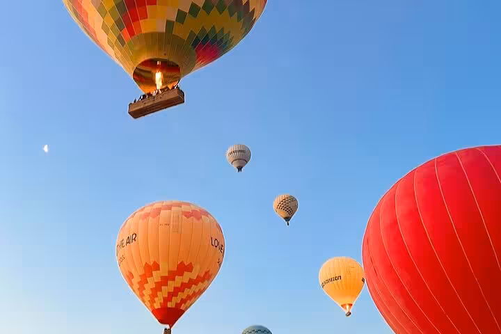 Colorful hot air balloons rising at sunrise in Luxor on a balloon ride tour with hotel pickup and drop-off