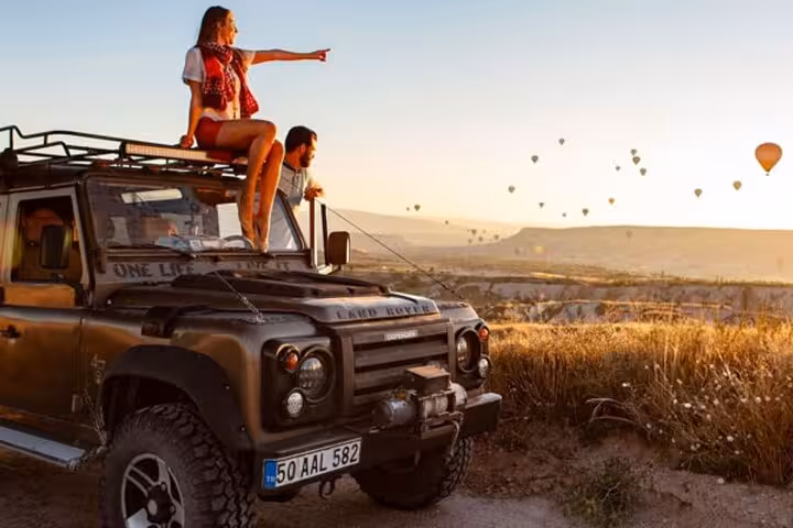 Sunrise Jeep safari in Cappadocia with hot air balloons as travelers ride on 4x4 for panoramic views