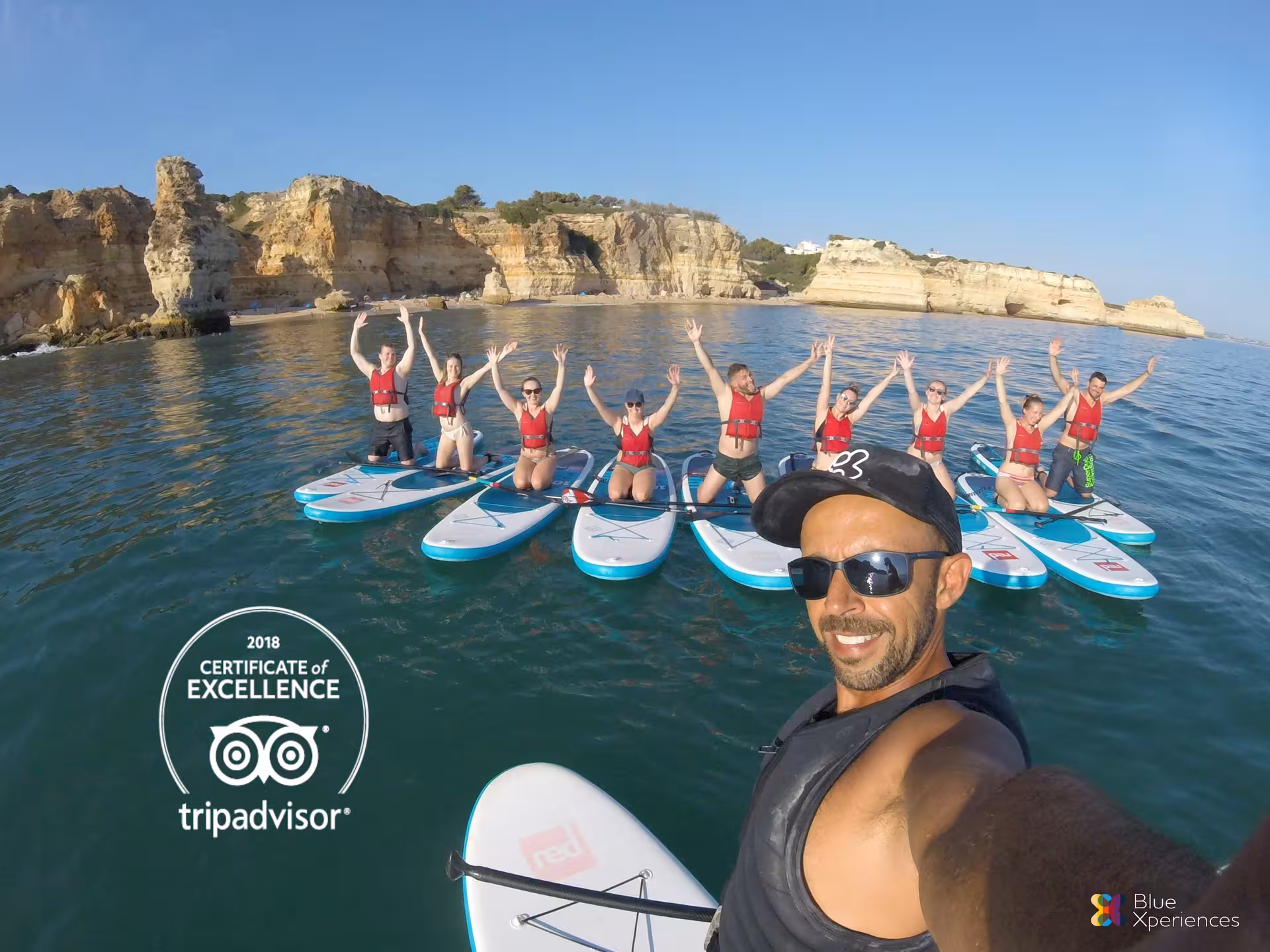 Sunrise paddleboarding tour near Benagil caves with happy group on SUP boards exploring Algarve coastline, Blue Xperiences