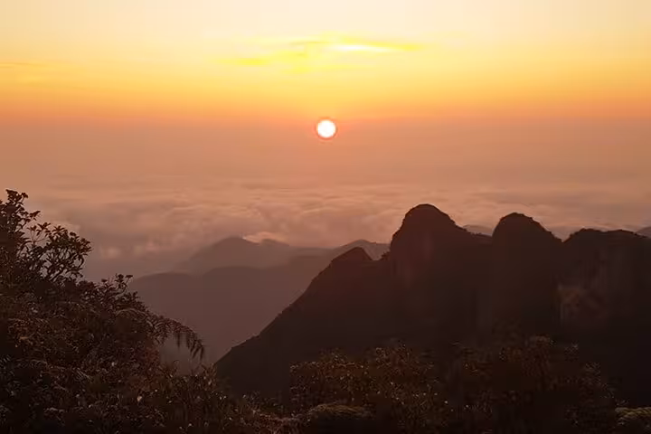Breathtaking sunrise view from Pedra da Macela with Paraty Tours, showcasing vibrant skies and lush mountain silhouettes.