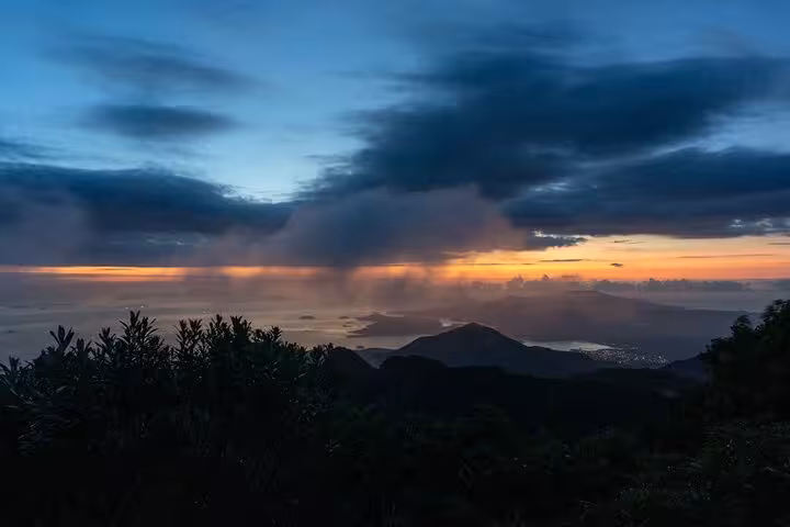 Dramatic sunrise over Pedra da Macela, Paraty, with lush vegetation and colorful clouds enhancing the vista.