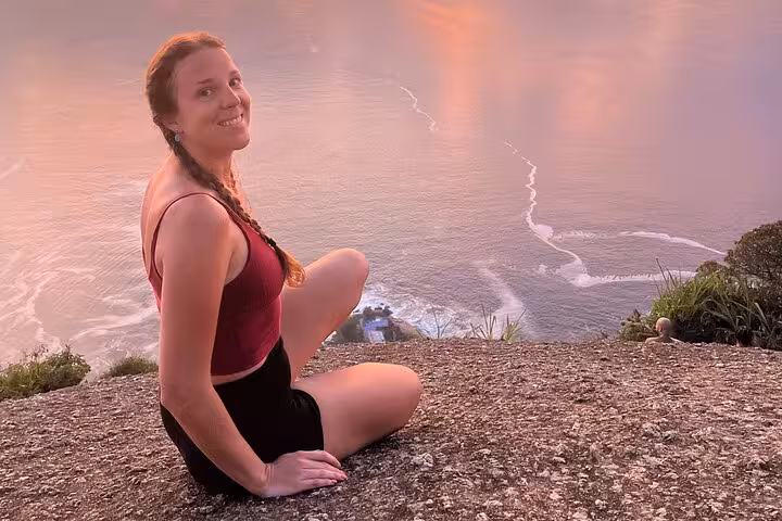 Woman relaxing at sunrise on Rio's Two Brothers, overlooking serene ocean views.