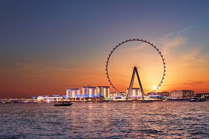 Sunset view of Ain Dubai, the world's largest observation wheel, illuminating the cityscape from the waterfront.