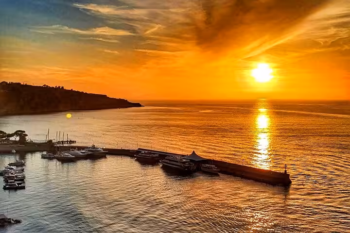 Golden sunset over Sorrento harbor with boats docked, perfect for a serene private sunset boat tour experience.