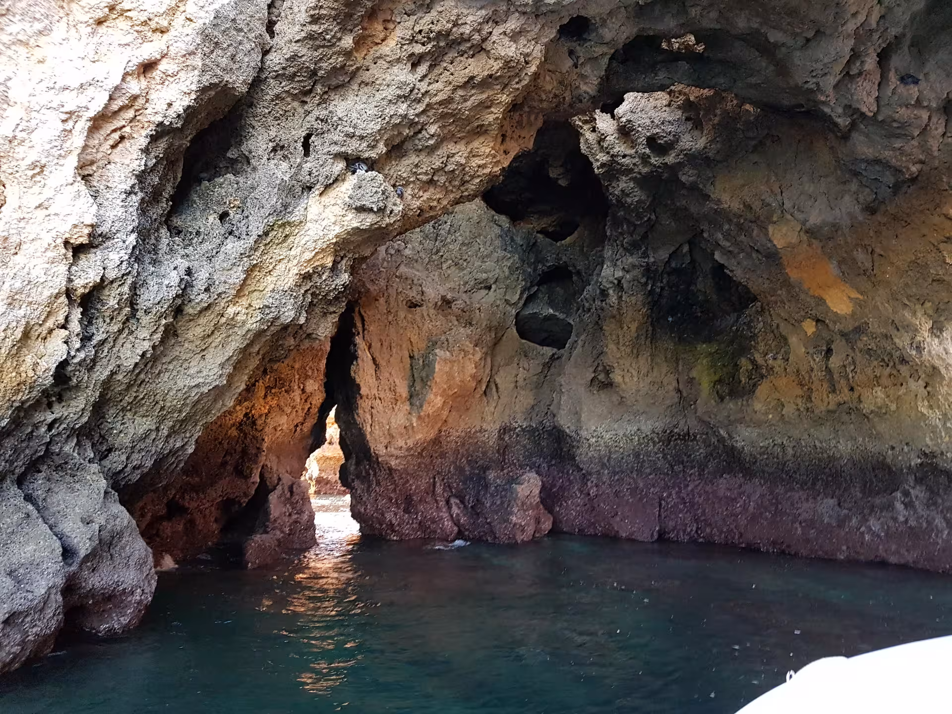 Twilight view of Lagos waterfront from a sunset boat trip, with city lights and calm Atlantic waters along Ponta da Piedade