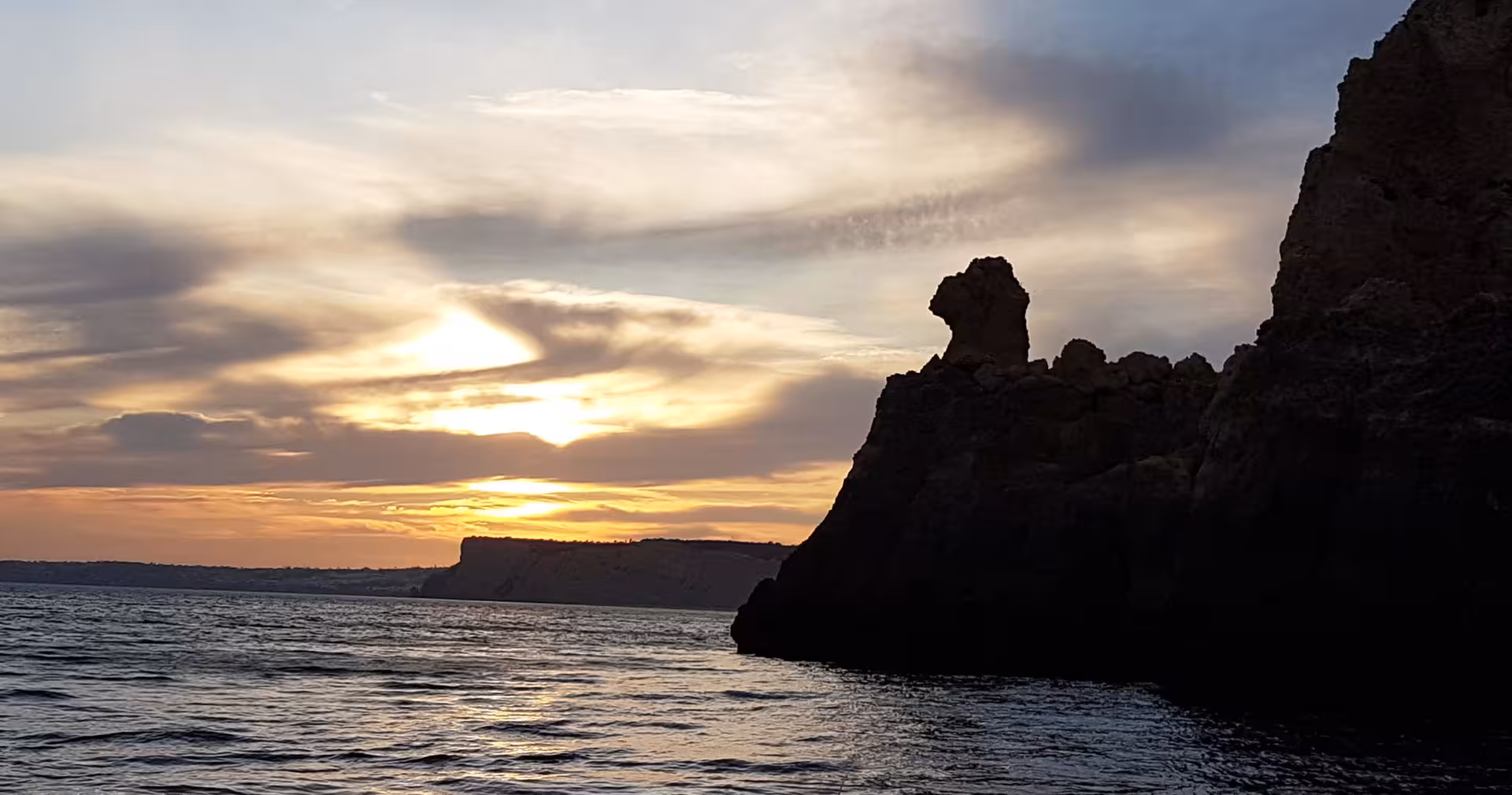 Dramatic rock formations at Ponta da Piedade, Lagos silhouetted against a vivid Algarve sunset on a coastal boat cruise