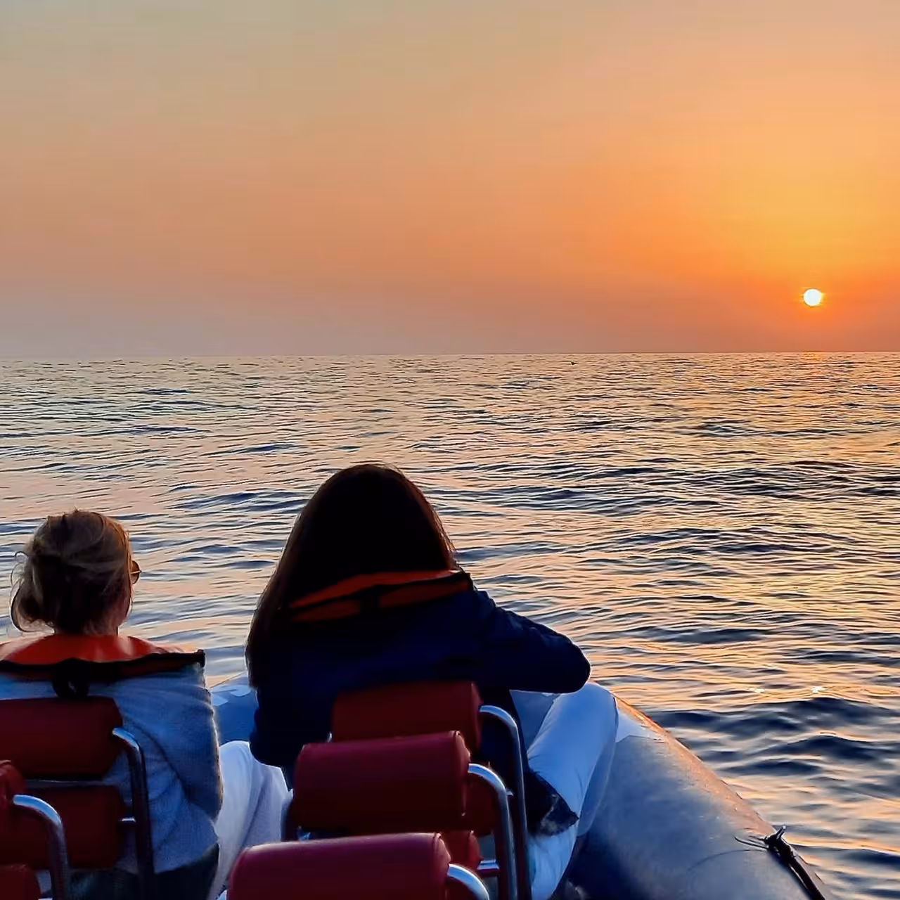 Tourists enjoy a breathtaking sunset over the Atlantic Ocean at Cabo S. Vicente, Portugal from a boat tour.