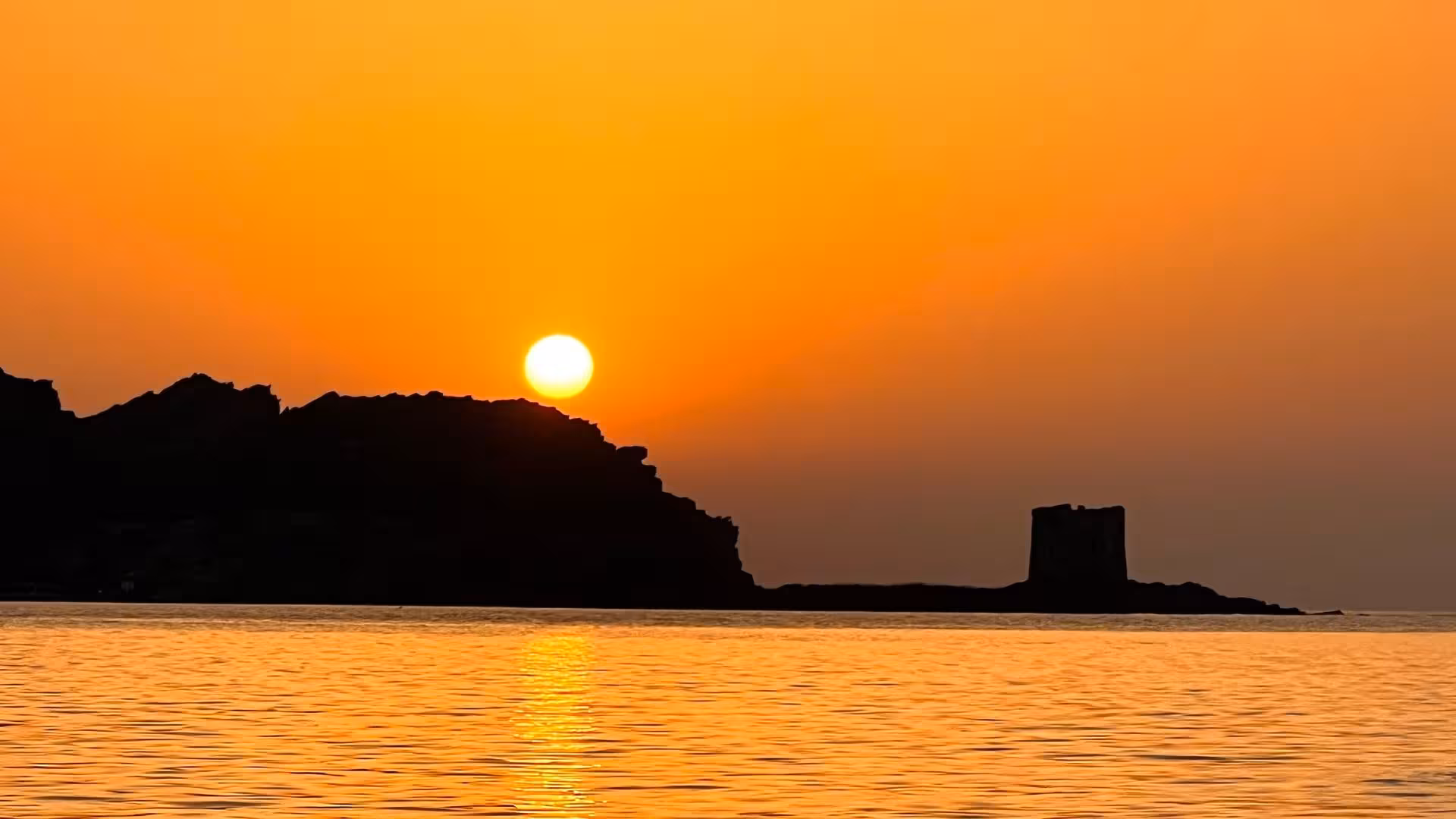 Stunning sunset over the Gulf of Asinara with silhouette of a historic tower, perfect for a catamaran tour from Stintino.
