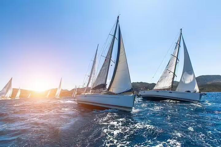 Sailboats gliding through vibrant waters at sunset on an exclusive 2-hour cruise from Barcelona, offering stunning sea views.