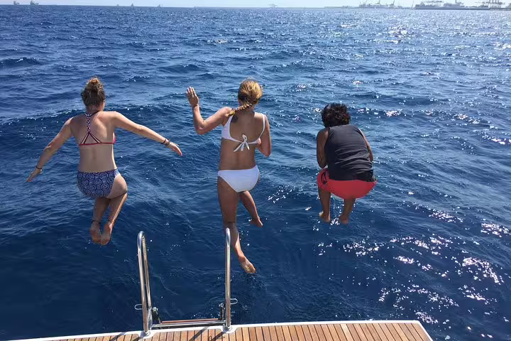 Guests enjoying a refreshing jump into the sea from a yacht during the Amazing 2-Hour Exclusive Sunset Cruise in Barcelona.