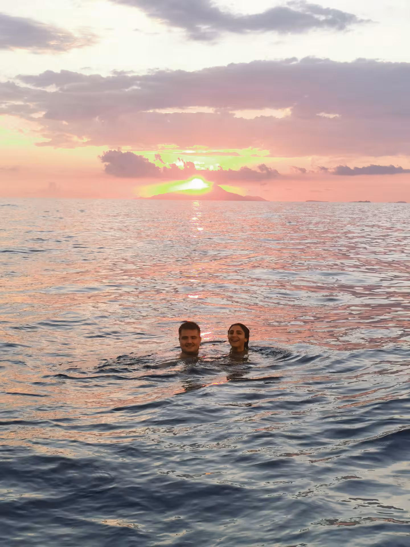 Couple swimming in the sea at sunset during an exclusive cruise from Sorrento, with Mount Vesuvius in the background.