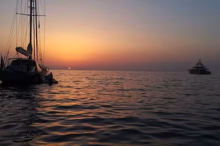 Serene sunset over the sea with sailboats, capturing the tranquil beauty of a Sorrento sunset cruise.